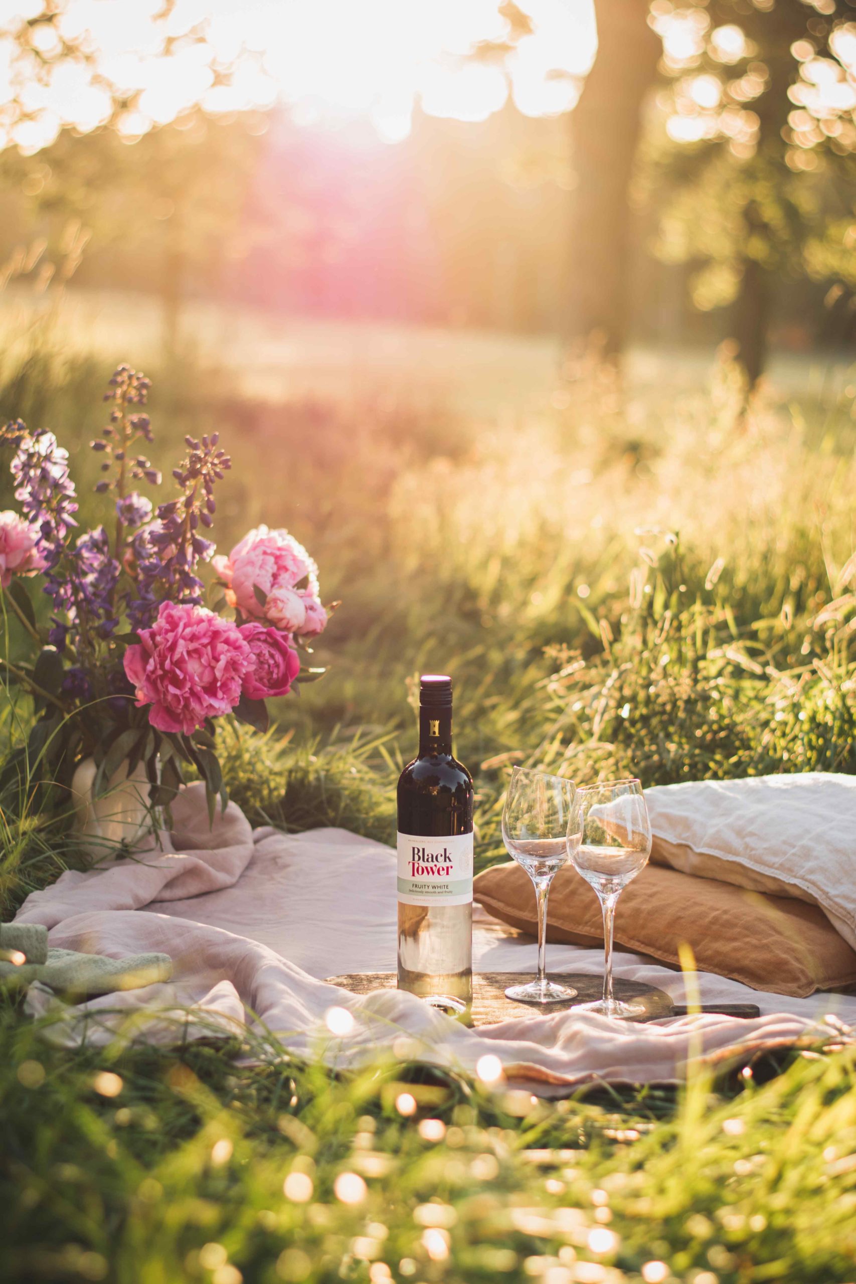 Bottle of Black Tower Wine in a picnic with wine glasses in a field with the sun shining, produced by YesMore wine digital marketing consultancy