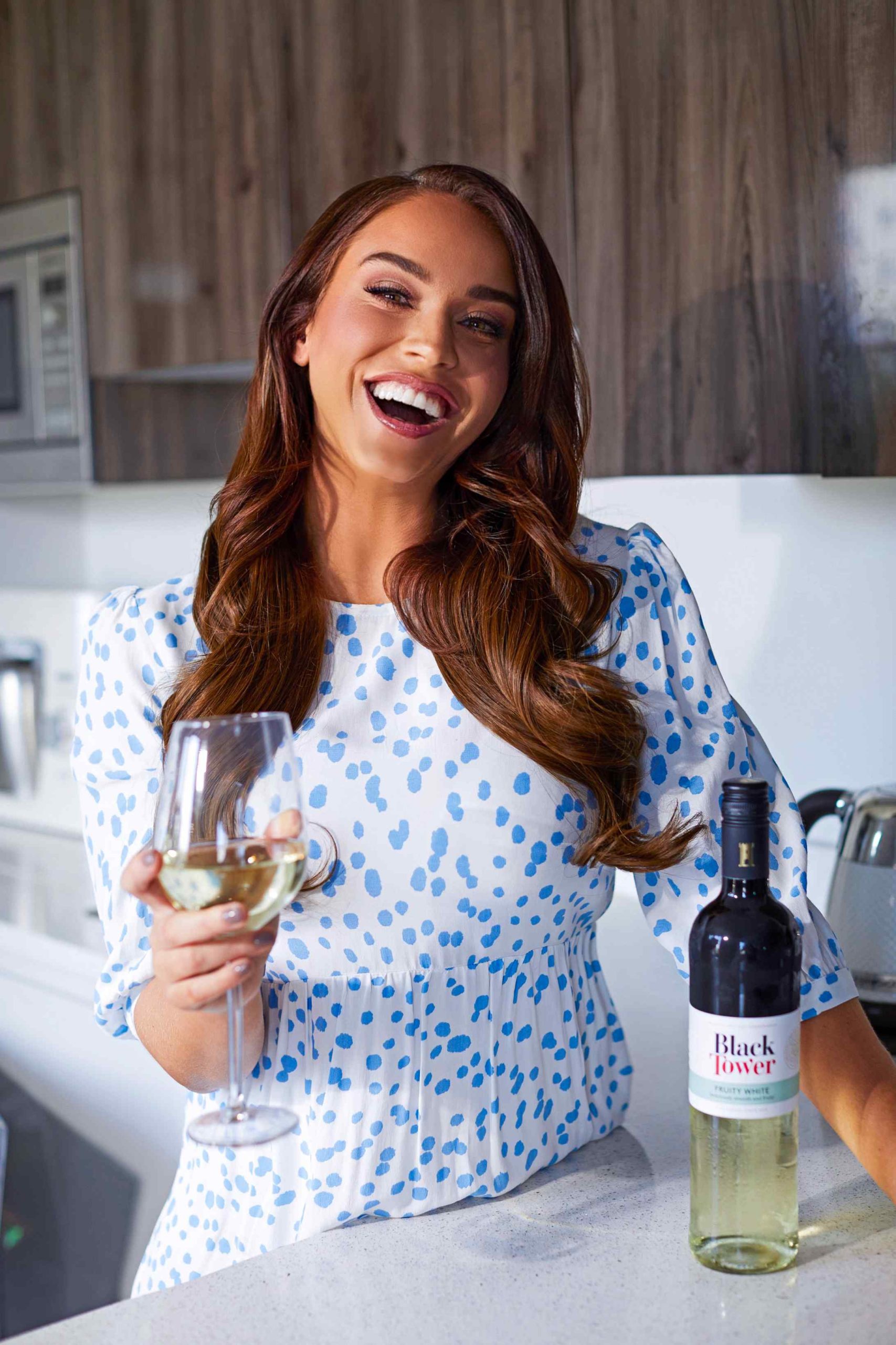 Vicky Pattison from Georgie Shore laughing whilst holding a glass of Black Tower Wine for a wine digital marketing campaign by YesMore Wine Advertising Agency