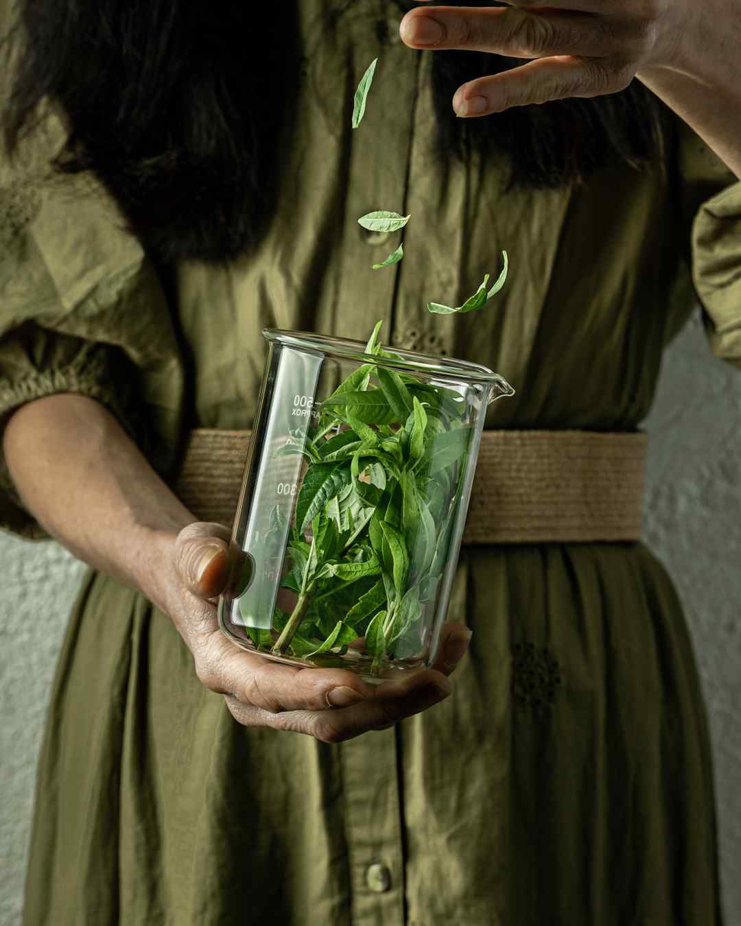 Woman in green dress dropping mint leaves into a glass jar as part of a content marketing shoot produced by YesMore Non Executive Directors for Cambridge Gin Distillery